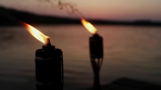 浪漫的日落湖。在码头上燃烧的火炬