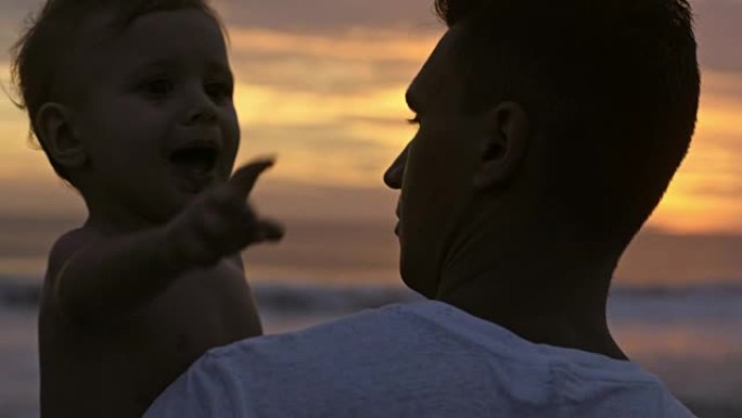 小男孩在父亲的怀抱中看着日落