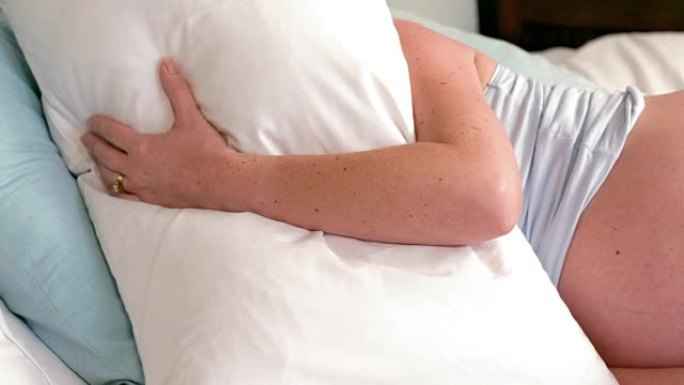 孕妇躺在床上用枕头遮住脸