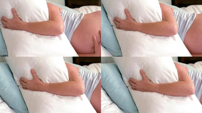 孕妇躺在床上用枕头遮住脸
