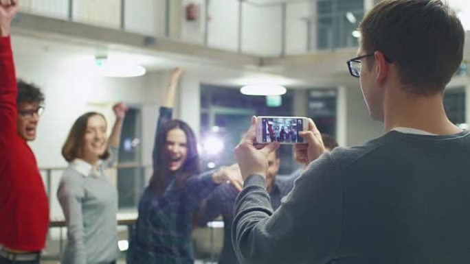 男学生正在用一群大学里的朋友的手机拍照。
