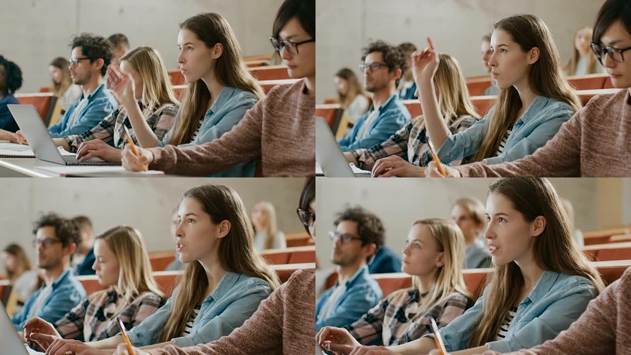 美丽的年轻学生在大学听讲座时使用笔记本电脑，她举手问讲师一个问题。多民族的现代光明学生。