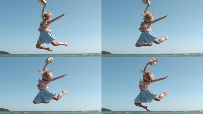 迷人的金发女郎拿着草帽在海滩上跳跃