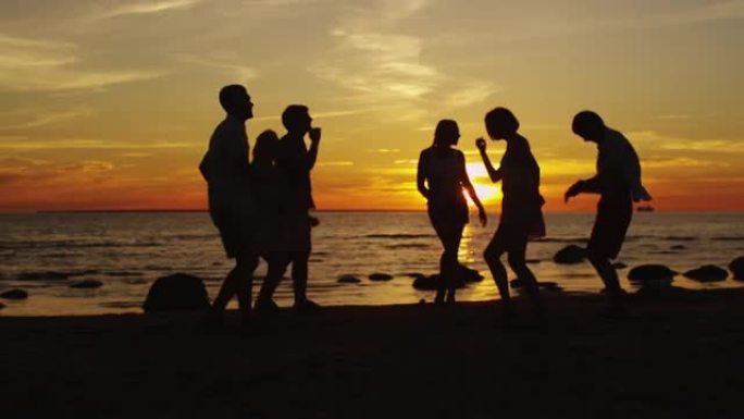 一群快乐的年轻人在日落的沙滩上跳舞