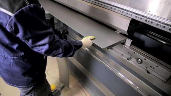 工人的手在工厂的现代弯曲工业机器上弯曲金属板