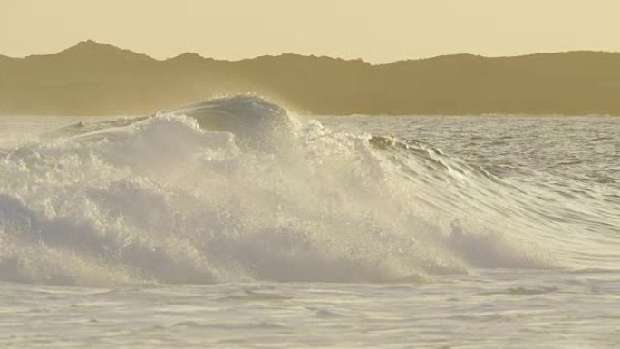 慢动作: 离岸风在橙色照明的日落时产生巨大的冲击波。