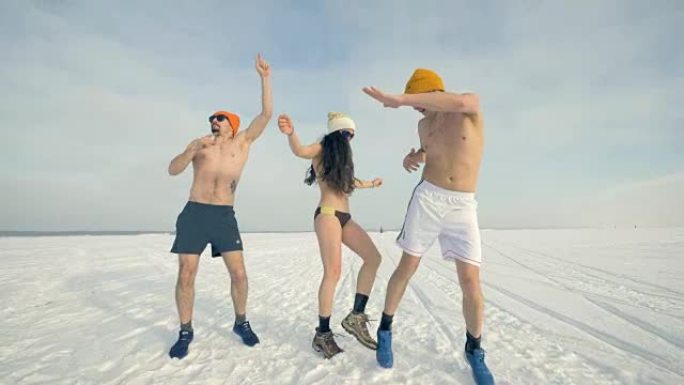 两个穿着比基尼的男人和一个女人在雪地上跳舞。4K。