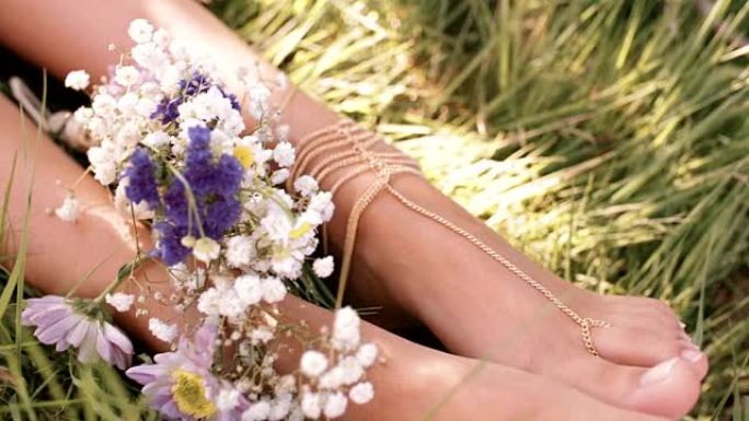 绿色草地上的女孩脚，鲜花和脚珠宝