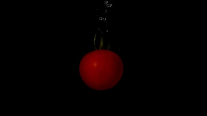 番茄在黑色背景下落入水中
