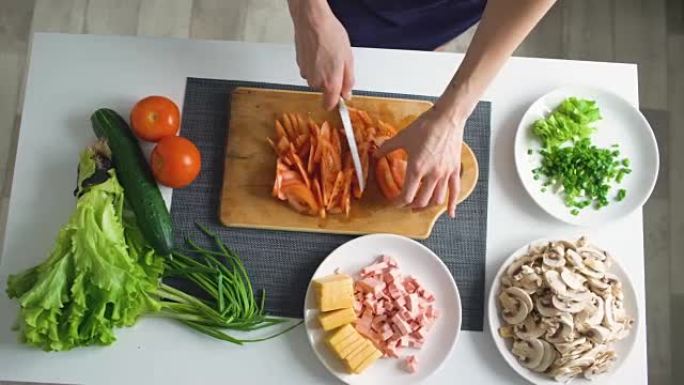 女人的手在家里的厨房里在木板上切蔬菜做披萨晚餐的俯视图