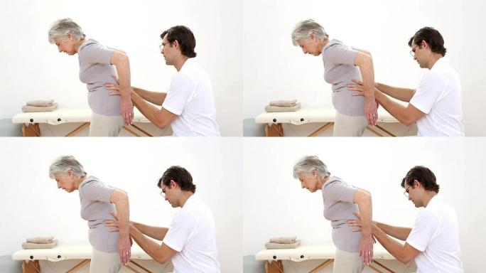 物理治疗师检查老年患者的腰部