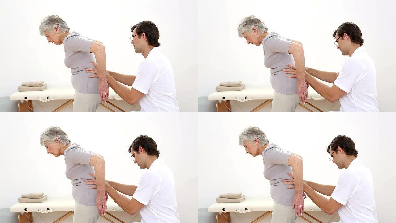 物理治疗师检查老年患者的腰部