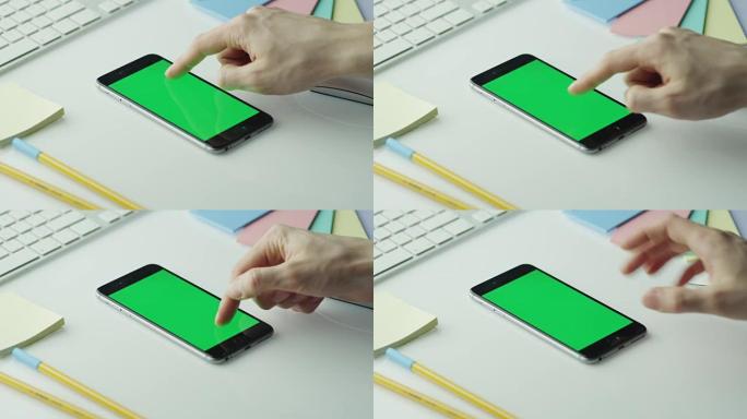 设计师正在纵向模式下使用带有绿屏的手机。顶视图。
