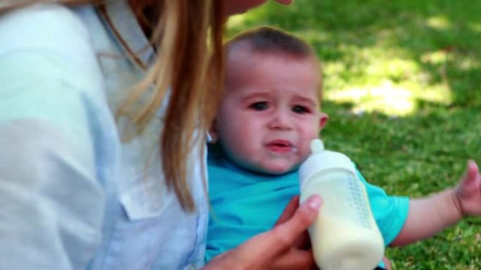 母亲给她可爱的宝贝儿子喂奶瓶