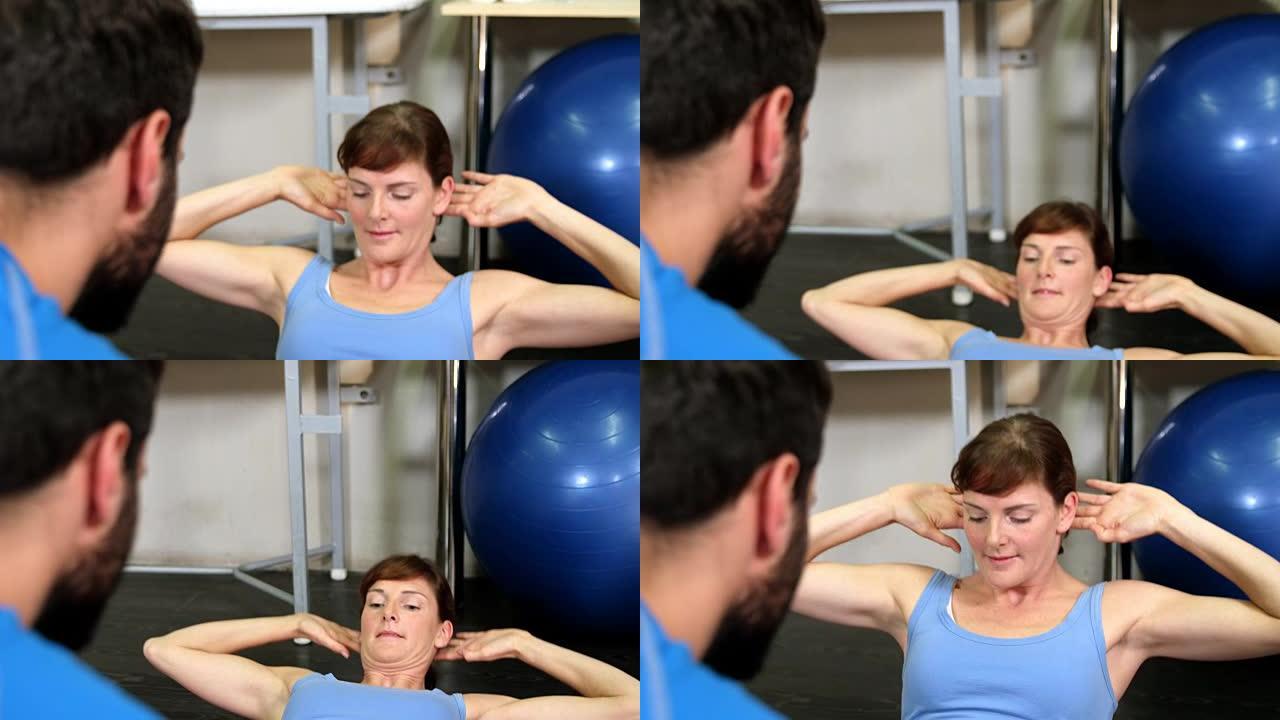 男性物理治疗师在锻炼时协助女性患者