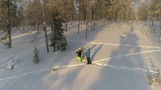 空中年轻人在阳光明媚的早晨穿着雪鞋探索白雪皑皑的拉普兰森林
