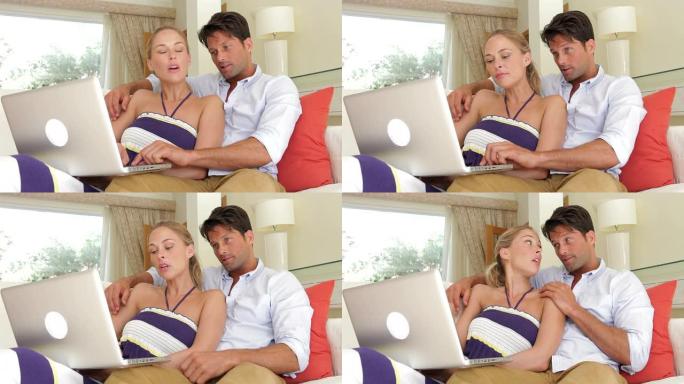夫妇坐在沙发上使用笔记本电脑