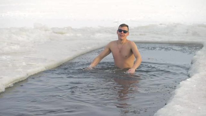 一个赤裸上身的男人在一个冰洞里泼水。