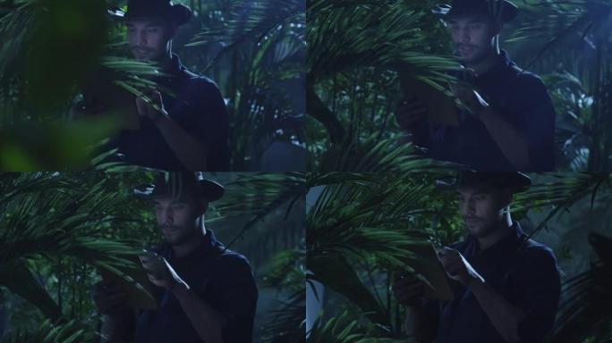 在丛林森林中使用平板电脑的帽子冒险家。
