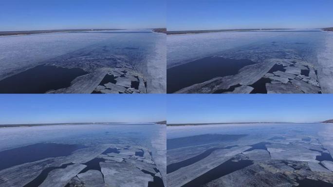 一条宽阔的冰冻河流，有些冰被打破了。