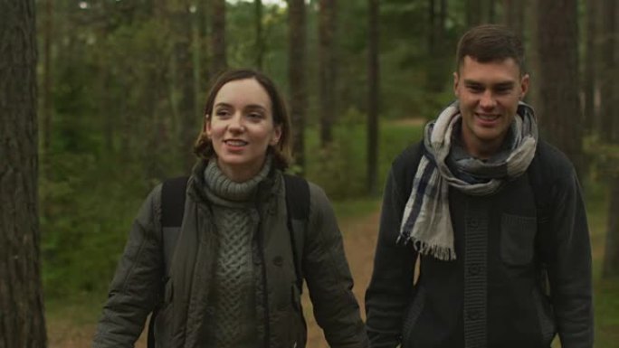夫妇在秋天的森林中以慢动作走向相机。