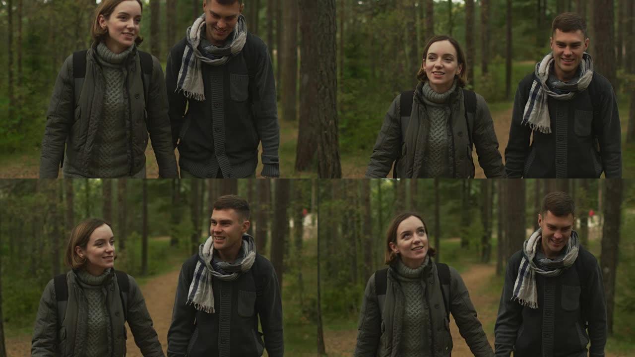 夫妇在秋天的森林中以慢动作走向相机。