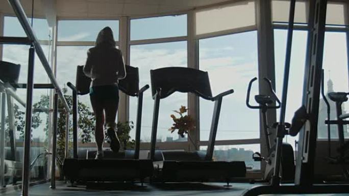 在运动健身房的跑步机上跑步的迷人女人
