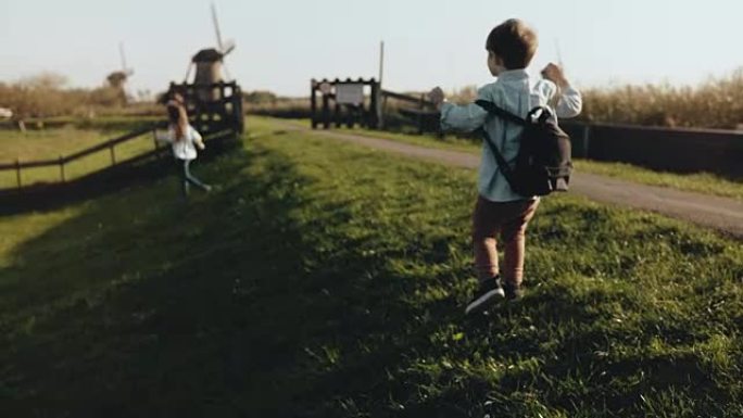 两个小孩在老风车农场附近玩耍。快乐的孩子在乡村风景中奔跑。幸福和快乐。4K