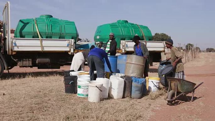 由于南非严重干旱，非洲人从一艘水车中收集集装箱中的水