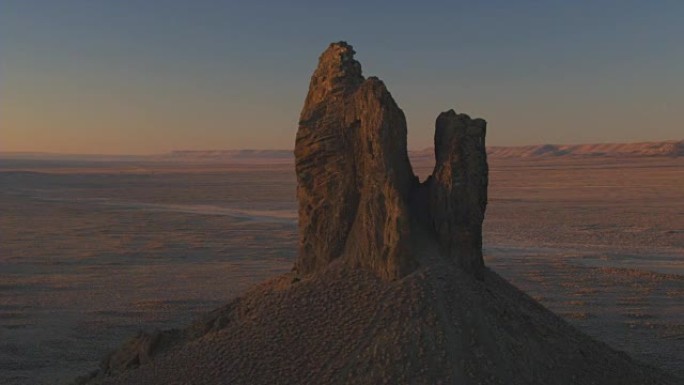 在金色日出时，在广阔的沙漠中围绕野猪象牙火山残余物进行空中飞行