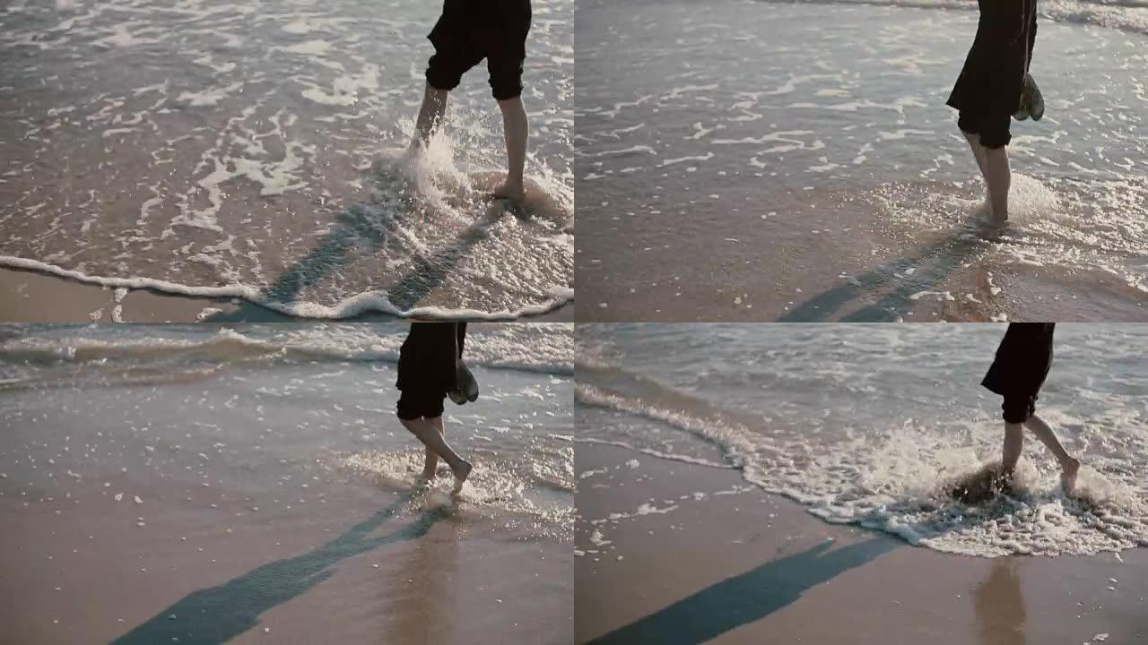 一个年轻人正走在美丽的海滩上，牛仔裤卷起来，把脚浸在海里