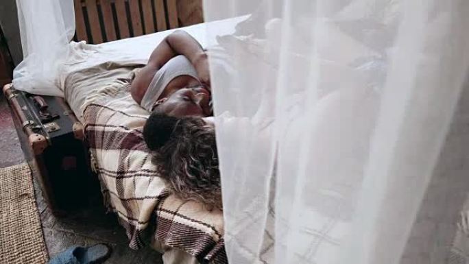 穿着睡衣的年轻多种族夫妇躺在床上看照片。男人和女人使用智能手机。透过窗帘观看