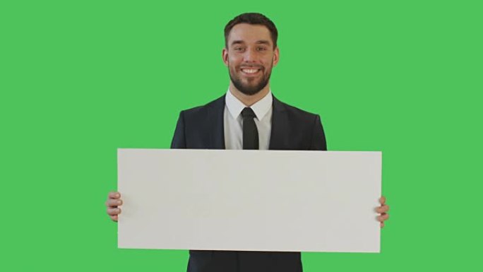 一个微笑的商人拿着海报/标语牌的中景照片。在绿色屏幕上拍摄。