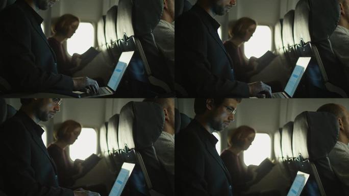 年轻人正在飞机上的笔记本电脑上工作，一个女人正在窗户旁边的背景中阅读。
