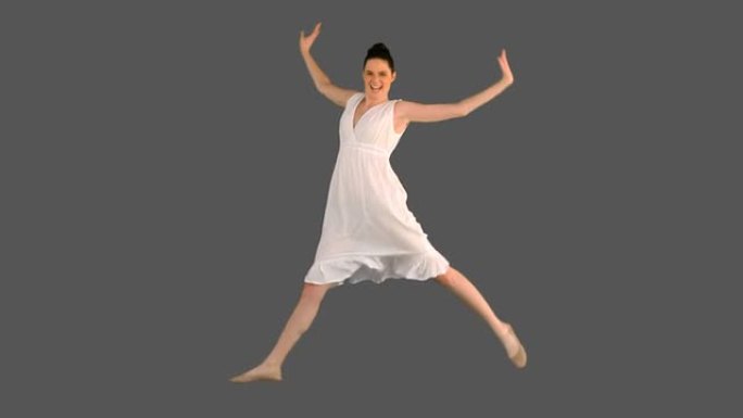 穿着白色连衣裙跳跃的年轻模特