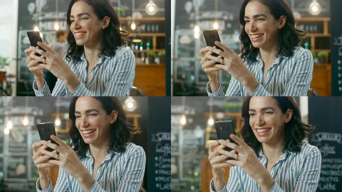 美丽的女人坐在咖啡馆里使用智能手机。她在给朋友或爱人发消息时微笑。在背景时尚的咖啡馆和忙碌的服务员。