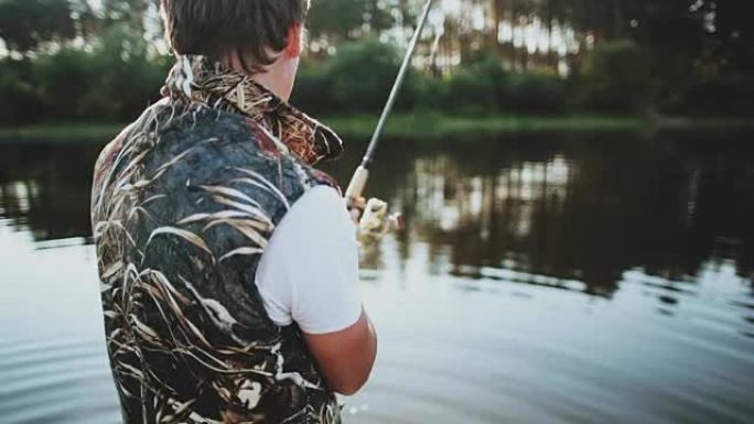 年轻人在湖边的橡皮船上抓鱼。雄性将钓鱼竿扔进水中并扭动卷轴