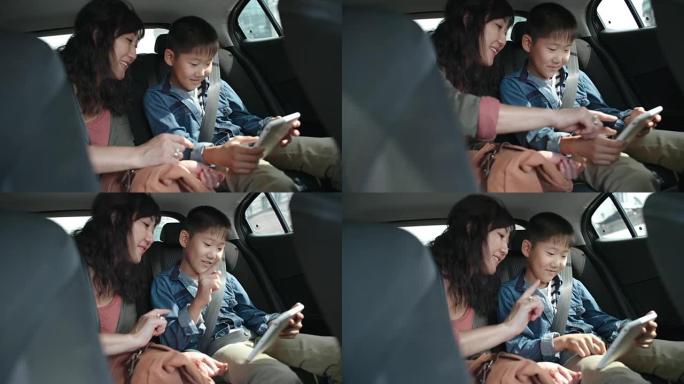 亚洲母亲与儿子一起乘车并使用平板电脑