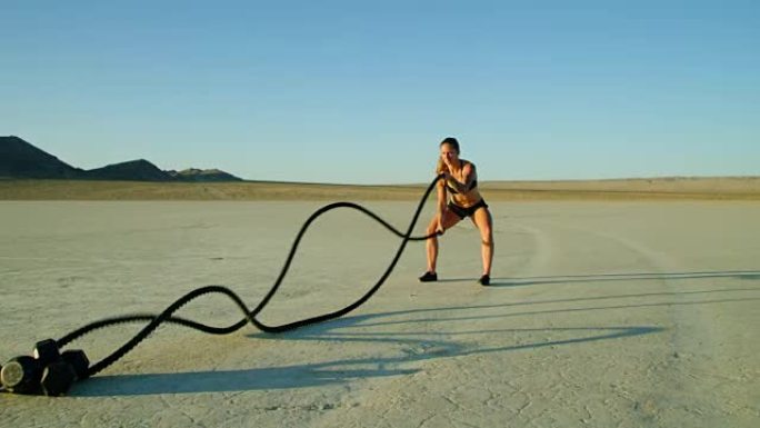慢动作运动女子在沙漠外面做极限战斗绳锻炼