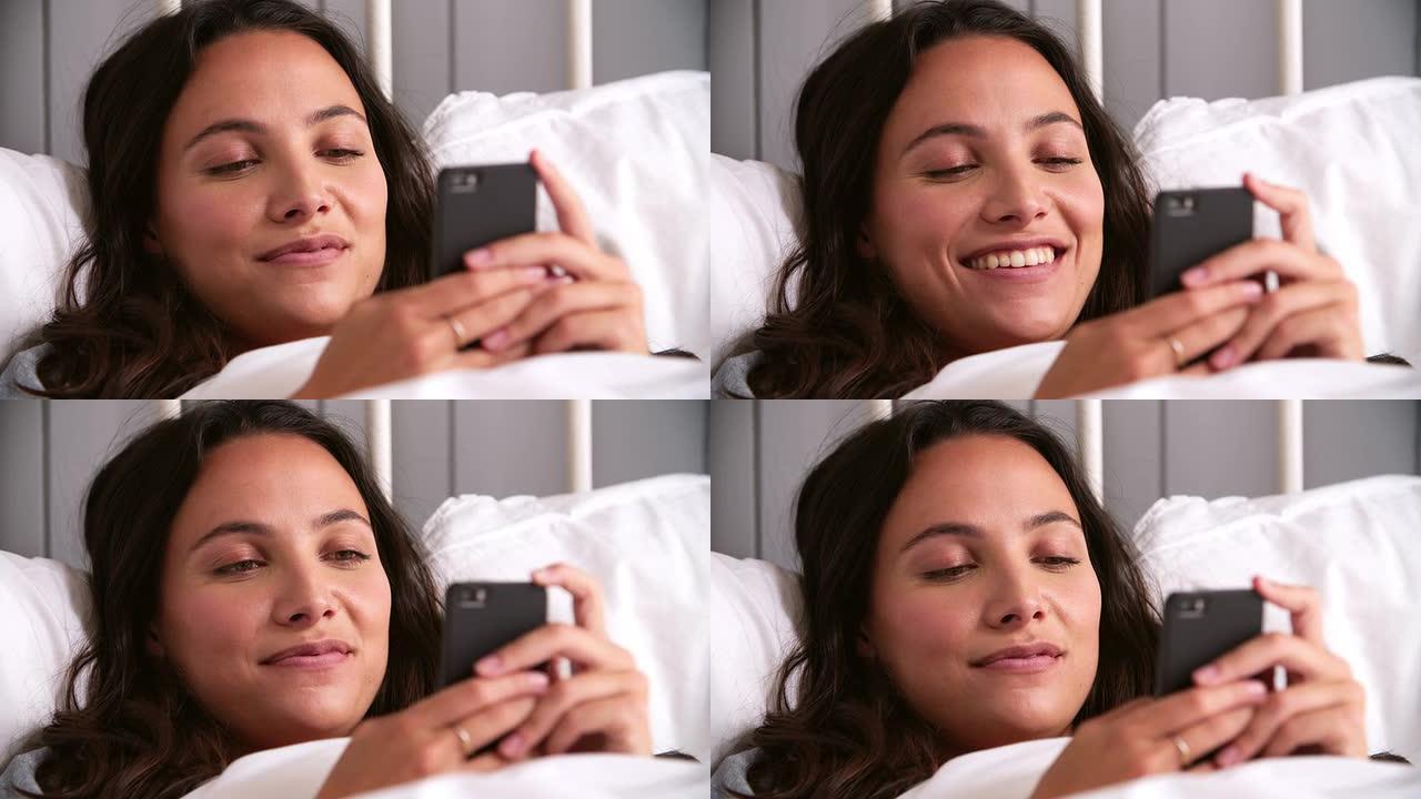 年轻女子躺在床上使用手机