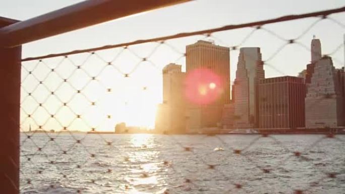 通过铁丝网观看日落时的曼哈顿天际线