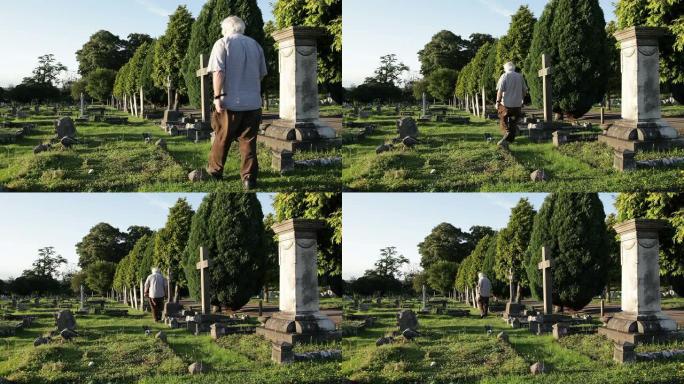 年长的男性走过墓地，站在坟墓旁