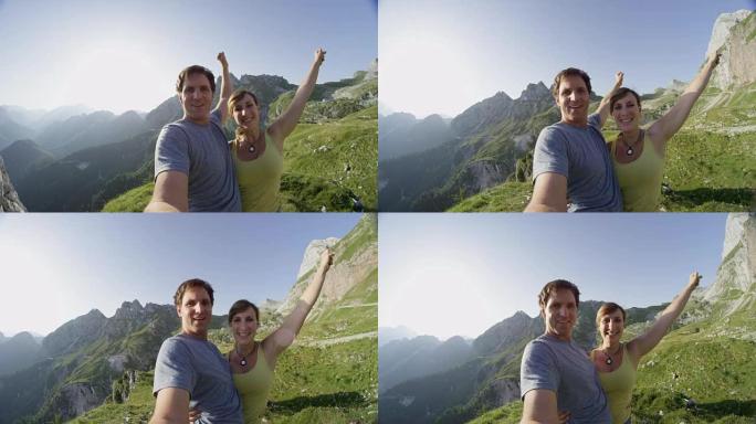 慢动作镜头耀斑: 快乐的年轻夫妇在山顶上伸出双臂。