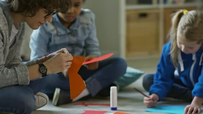 幼儿在幼儿园老师的帮助下做纸艺