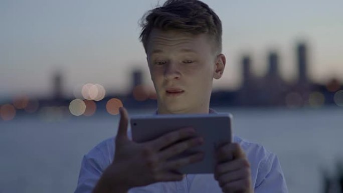 快乐的男人在网上和他的朋友聊天。在公共场所使用数字平板电脑应用进行视频聊天。