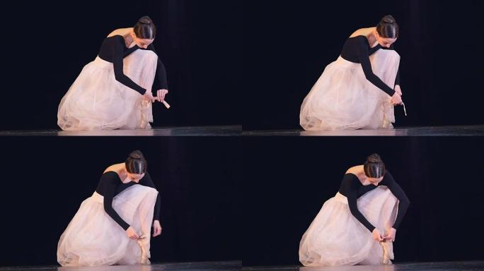 一个芭蕾舞演员把她的白鞋绑起来。