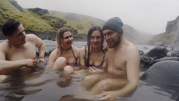 冰岛的温泉地热水疗中心。两对旅行夫妇在冰岛的热水池放松。享受沐浴的游客