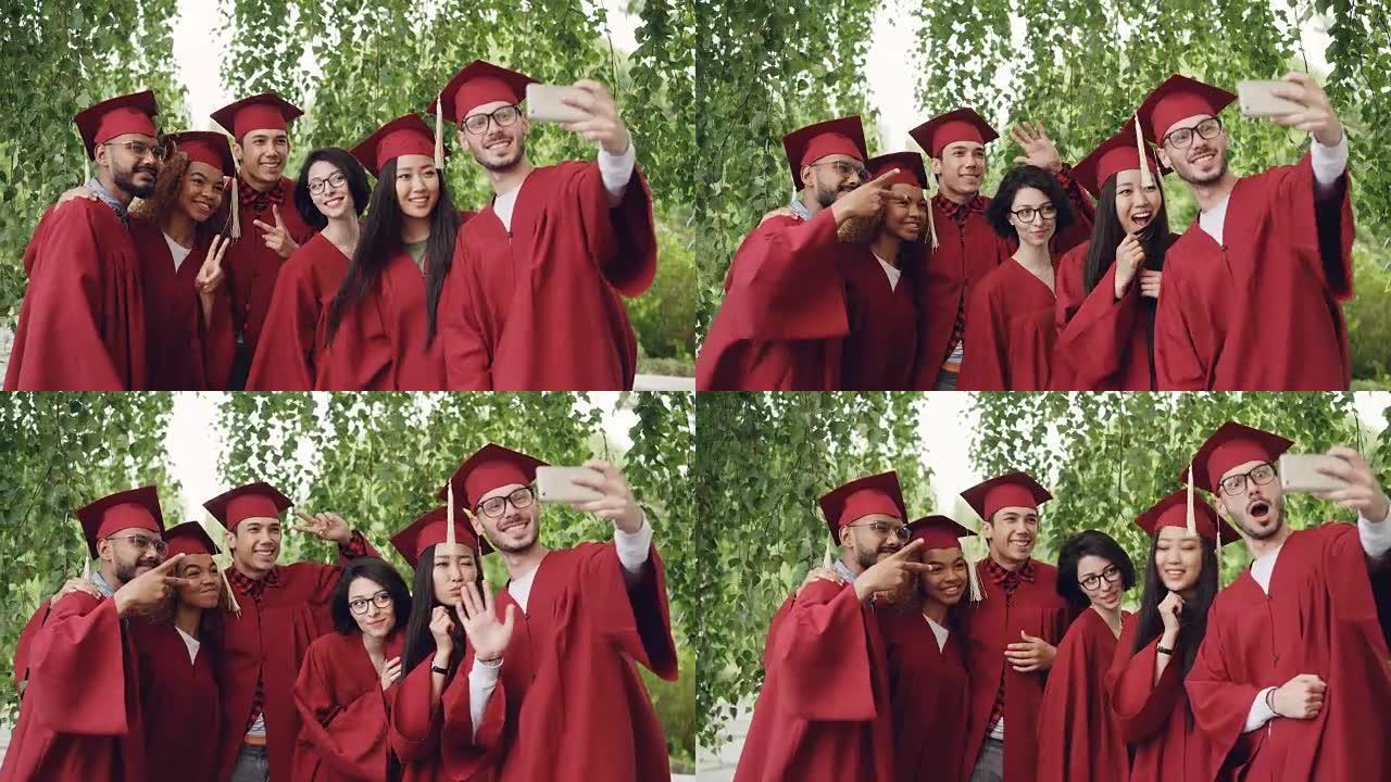 欢快的朋友即将毕业的学生正在用智能手机自拍，年轻人正在摆姿势，展示手势，做鬼脸和大笑。