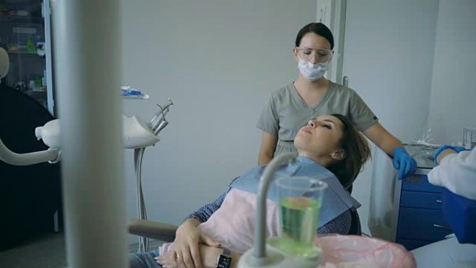 牙科治疗结束后，医生抬起牙科椅。年轻女性到牙科医生处接受口腔检查