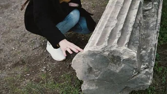 女人正在意大利罗马的一个古老城堡的院子里探索。女孩触摸古董和真实的柱子